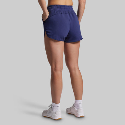Person wearing navy athletic shorts on a gray background