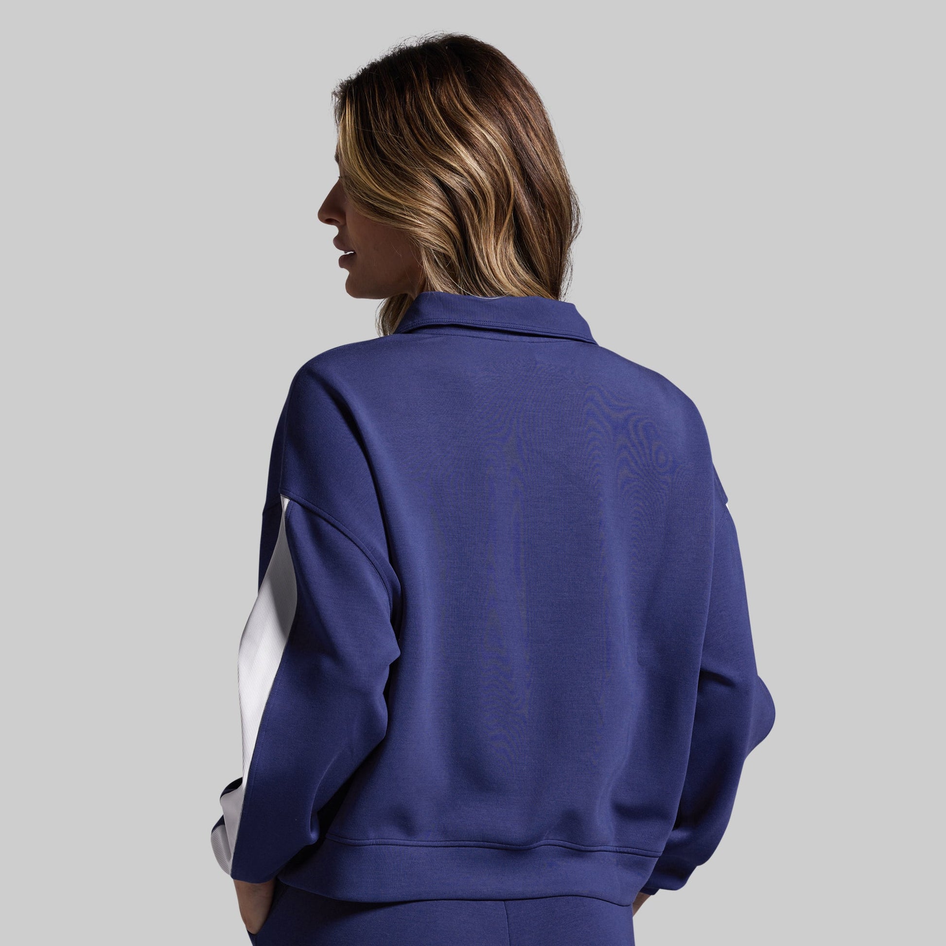Person wearing a blue pullover with white stripes on a gray background