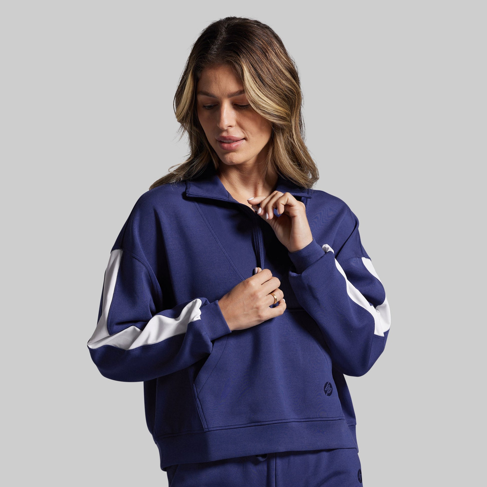 Woman wearing a blue sweatshirt with white accents on a gray background