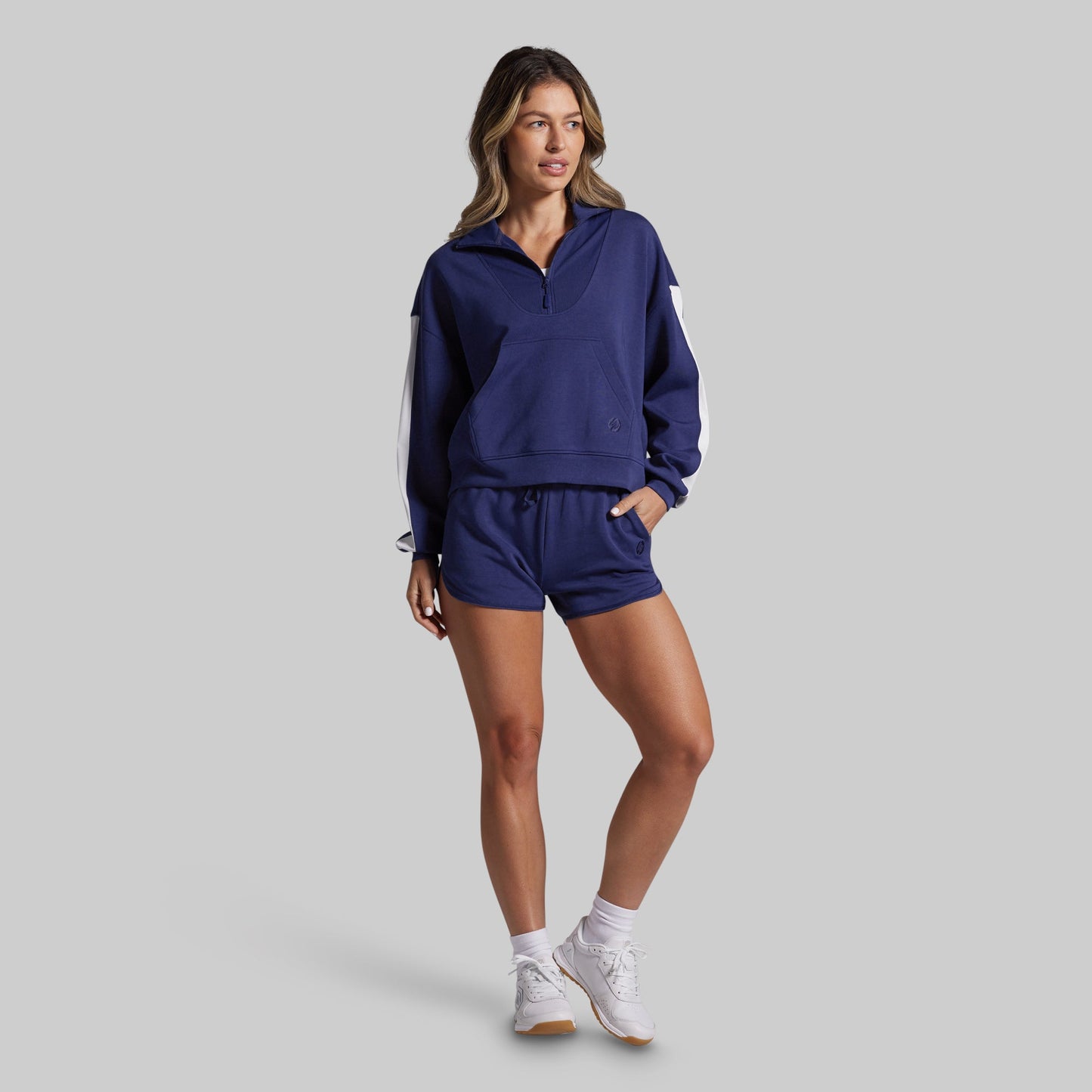 Woman wearing a navy tracksuit on a gray background