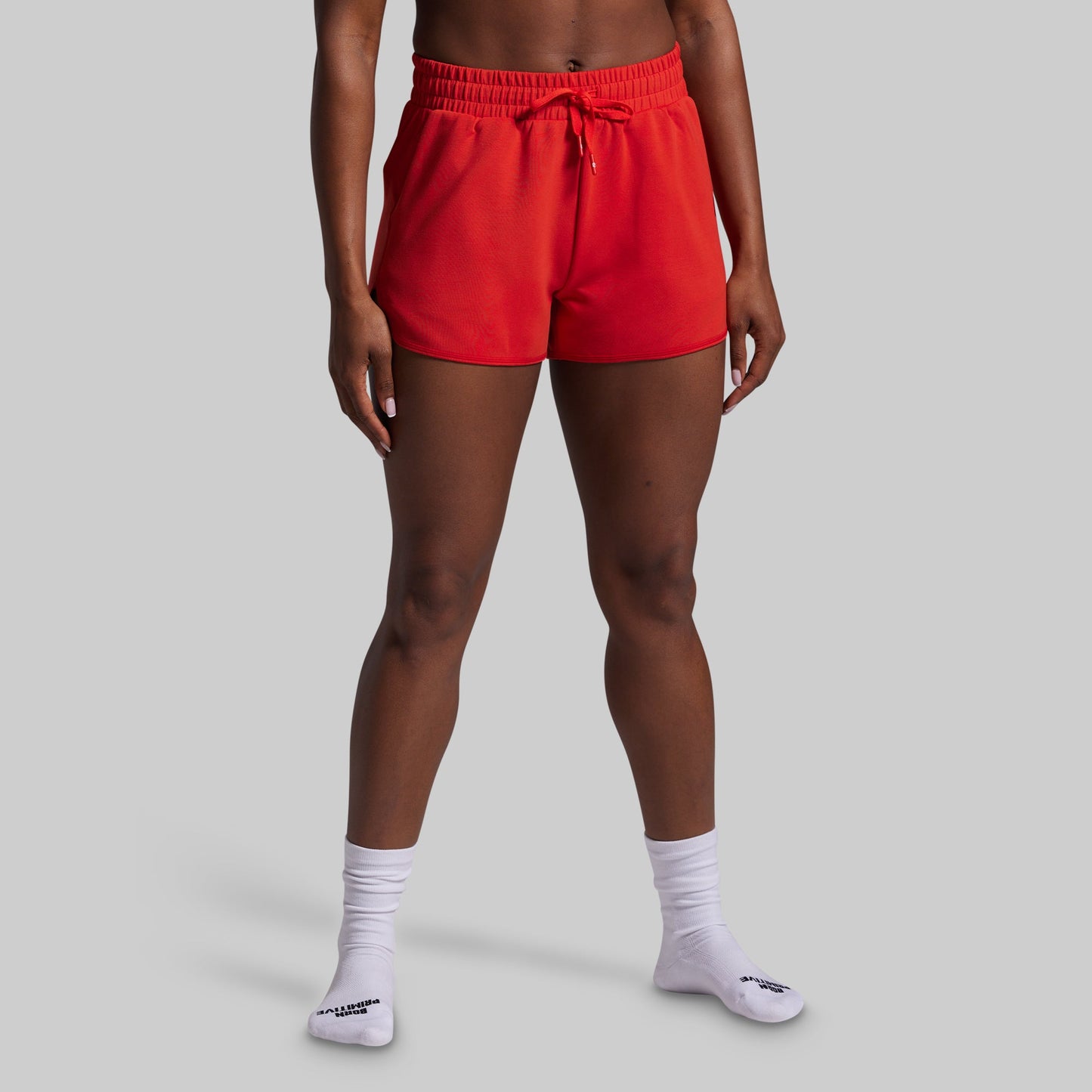 Person wearing red shorts and white socks on a gray background