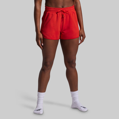 Person wearing red shorts and white socks on a gray background