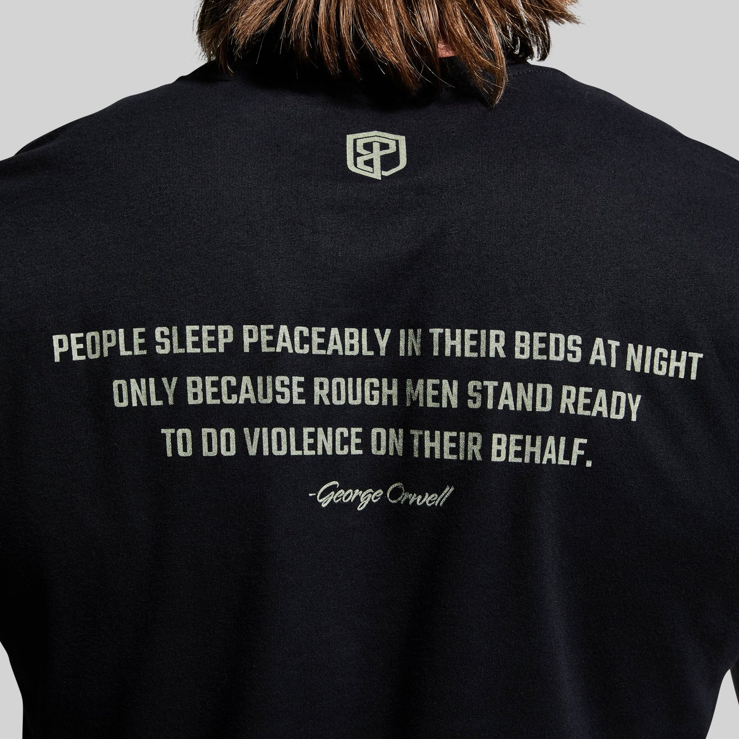 Black t-shirt with a quote and logo on the back, worn by a person.