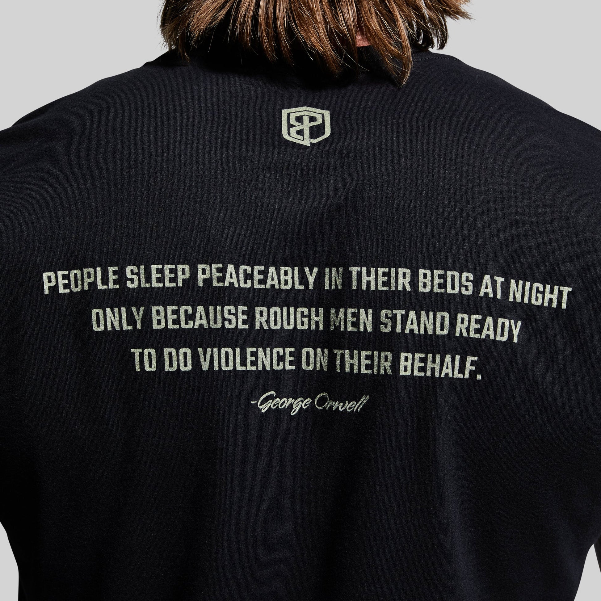 Black t-shirt with a quote and logo on the back, worn by a person.