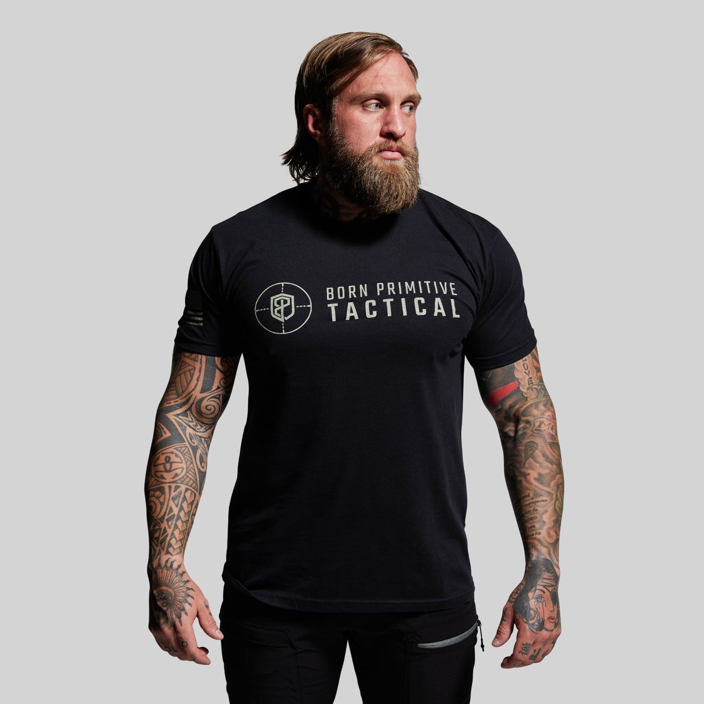 Man wearing a black t-shirt with 'Born Primitive Tactical' logo on a gray background