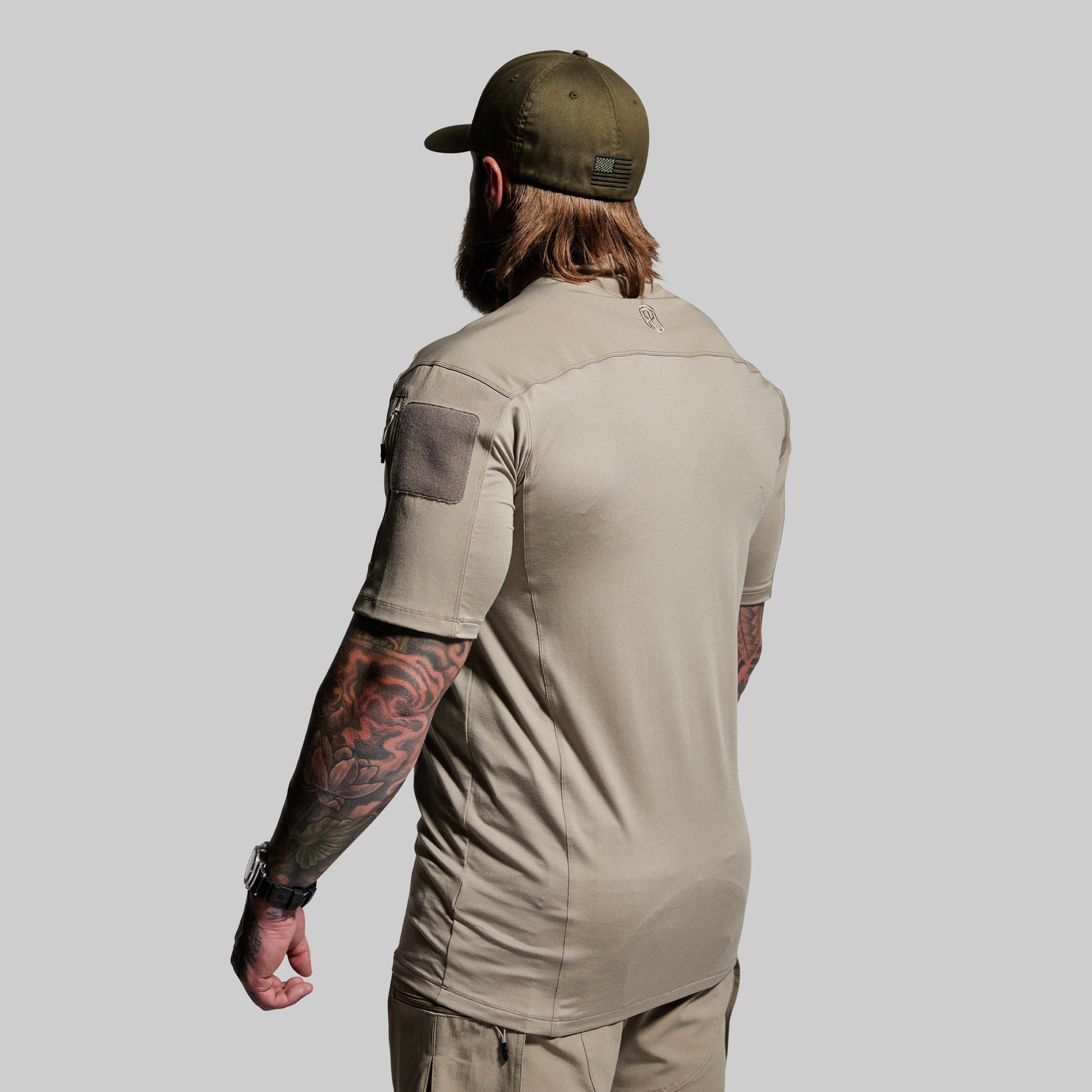 Man wearing a beige short sleeve shirt and cap on a gray background