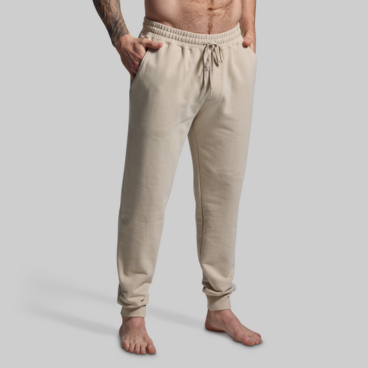 Beige jogger pants worn by a person on a plain background