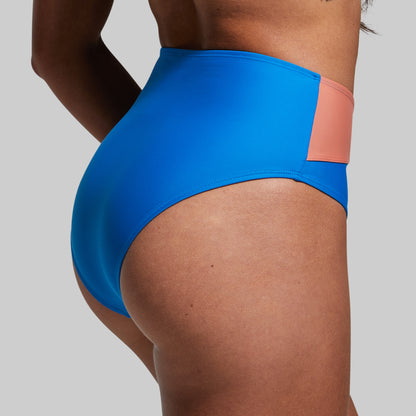 Woman wearing a blue bikini bottom on a gray background