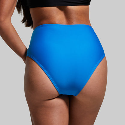 Woman wearing a blue bikini bottom on a gray background