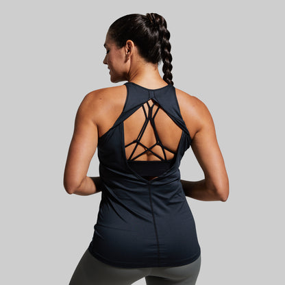 Woman wearing a black athletic tank top with open back design on a gray background