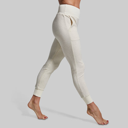 White textured joggers worn by a person on a plain background