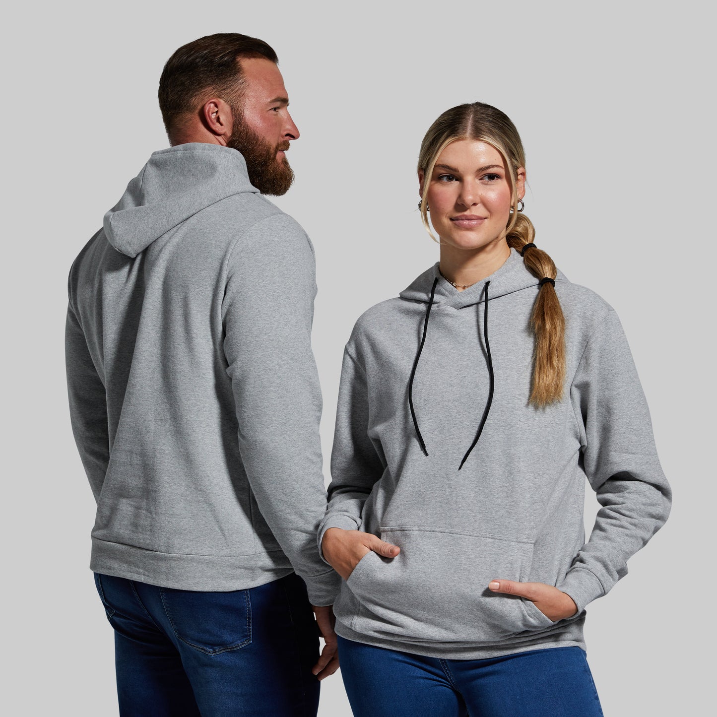 Two people wearing gray hoodies against a plain background