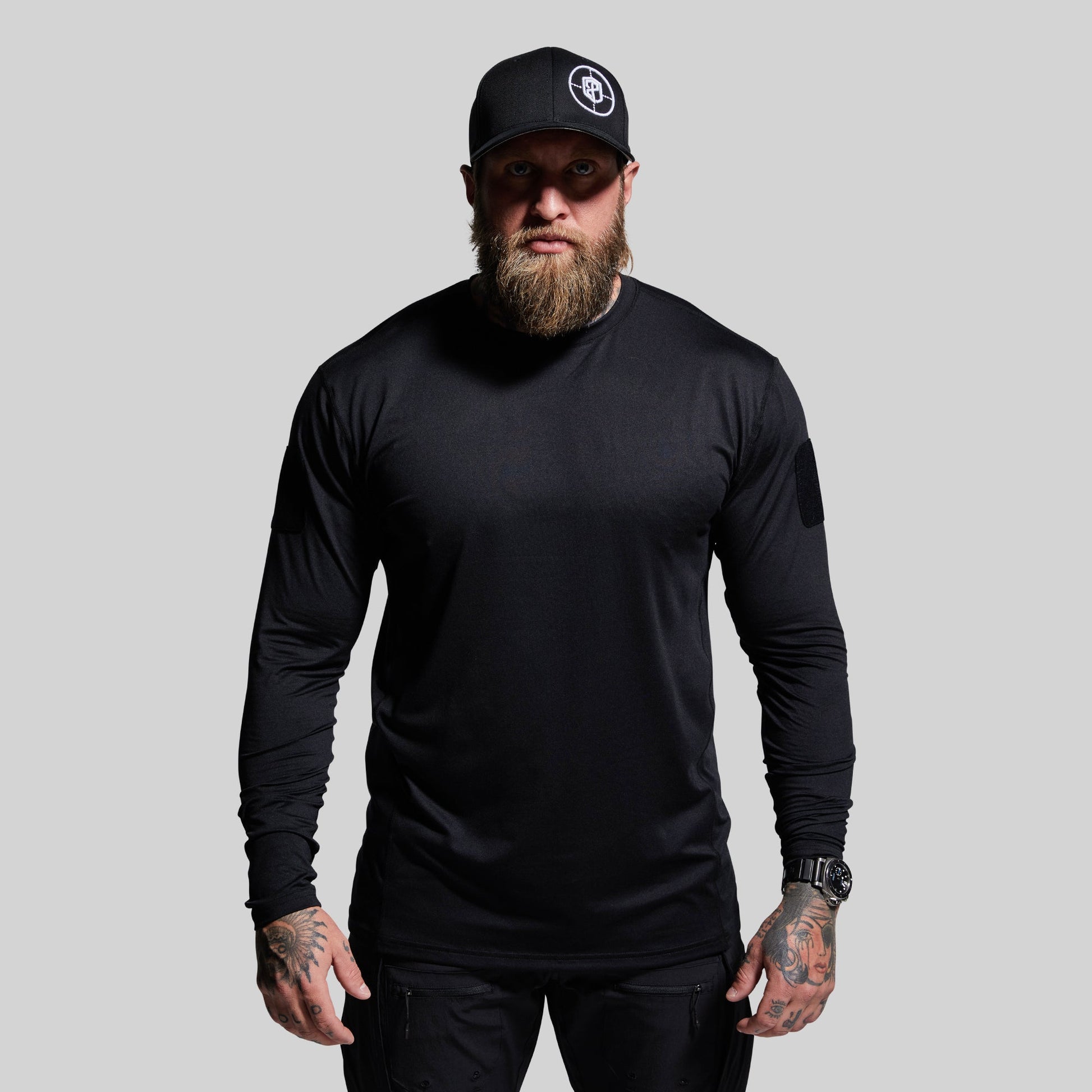 Man wearing a black long-sleeve shirt and cap on a gray background