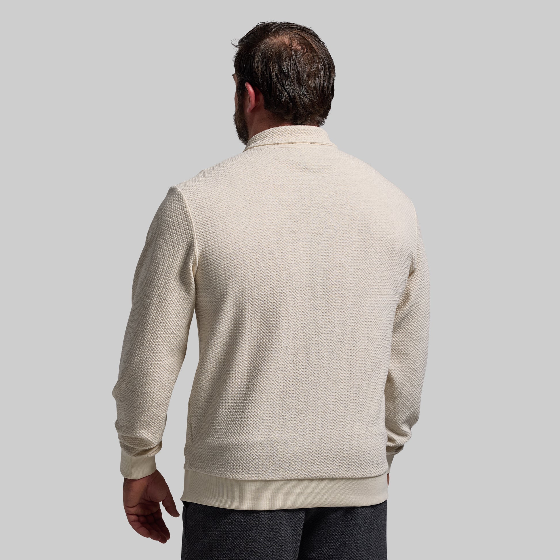 Man wearing a beige textured sweater against a plain background
