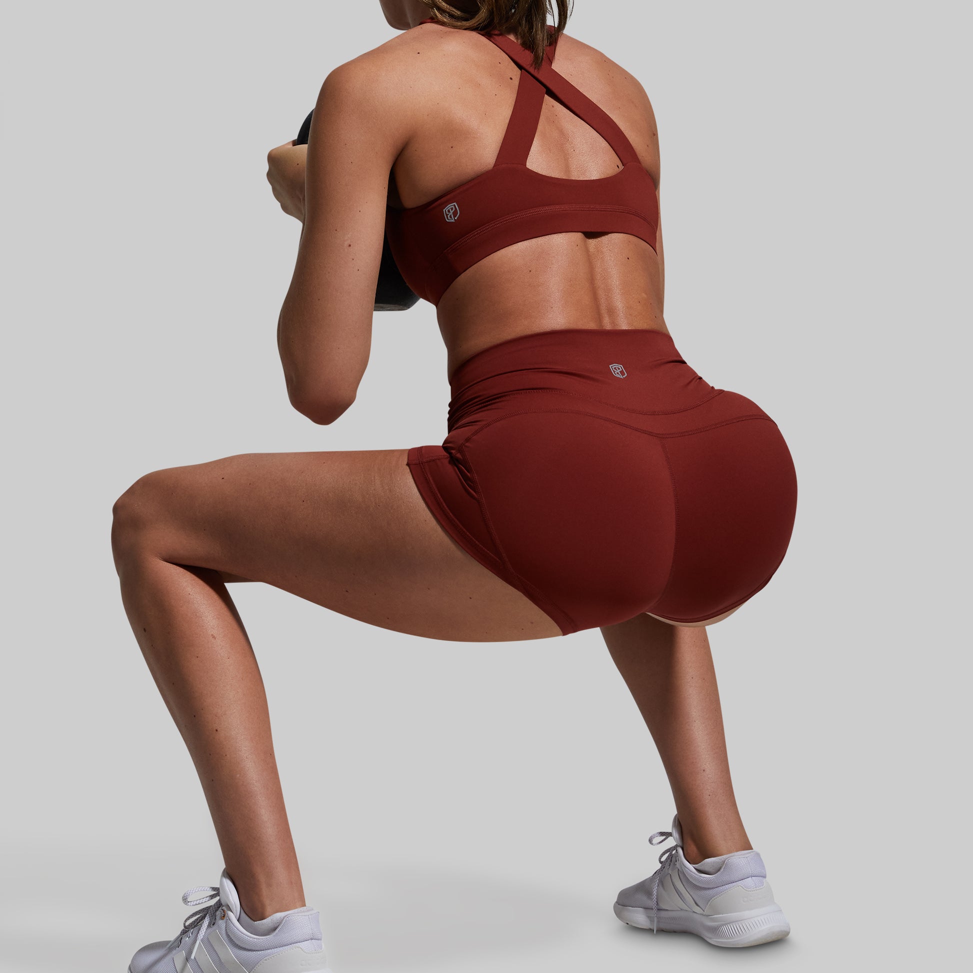 Person wearing a red sports bra and shorts on a gray background