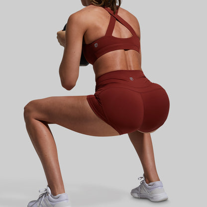 Person wearing a red sports bra and shorts on a gray background