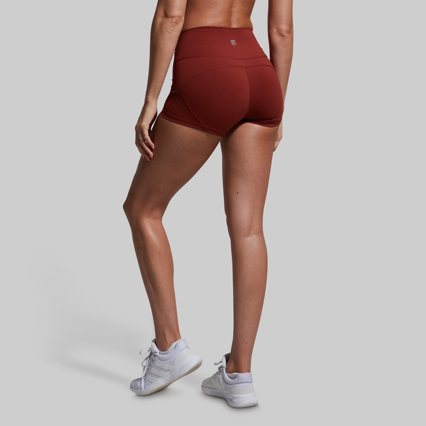Person wearing maroon athletic shorts on a gray background