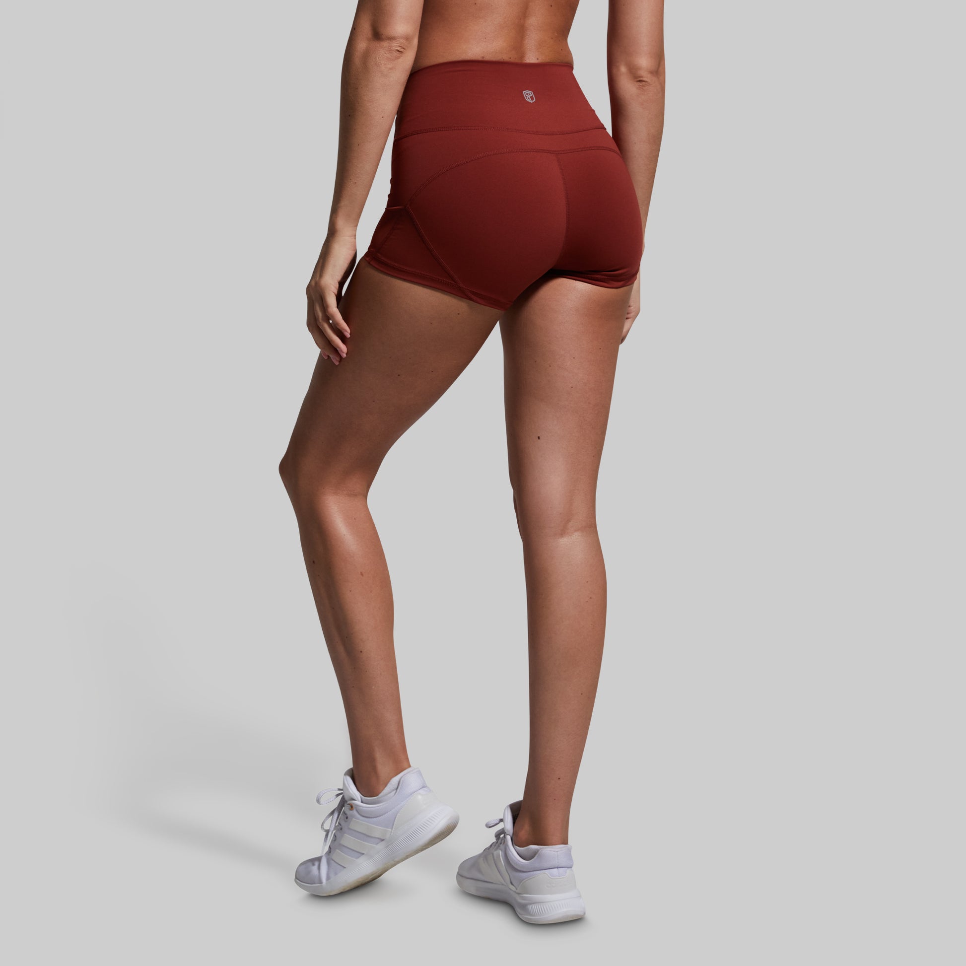 Person wearing maroon athletic shorts on a gray background