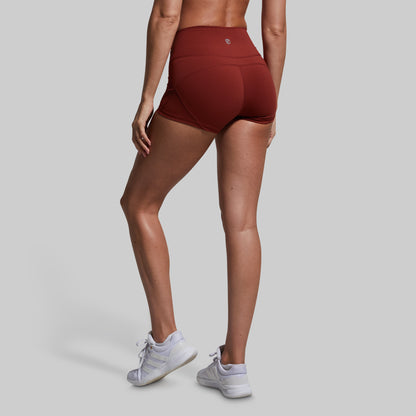 Person wearing maroon athletic shorts on a gray background