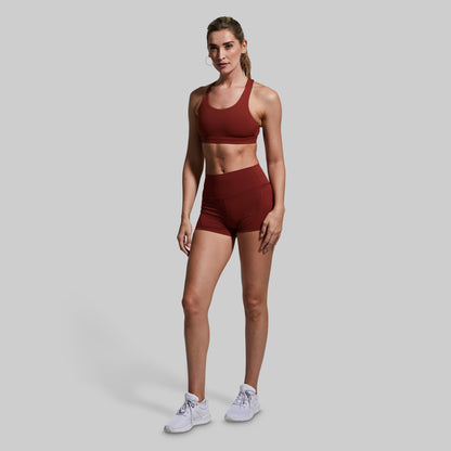 Woman wearing a maroon athletic outfit on a gray background