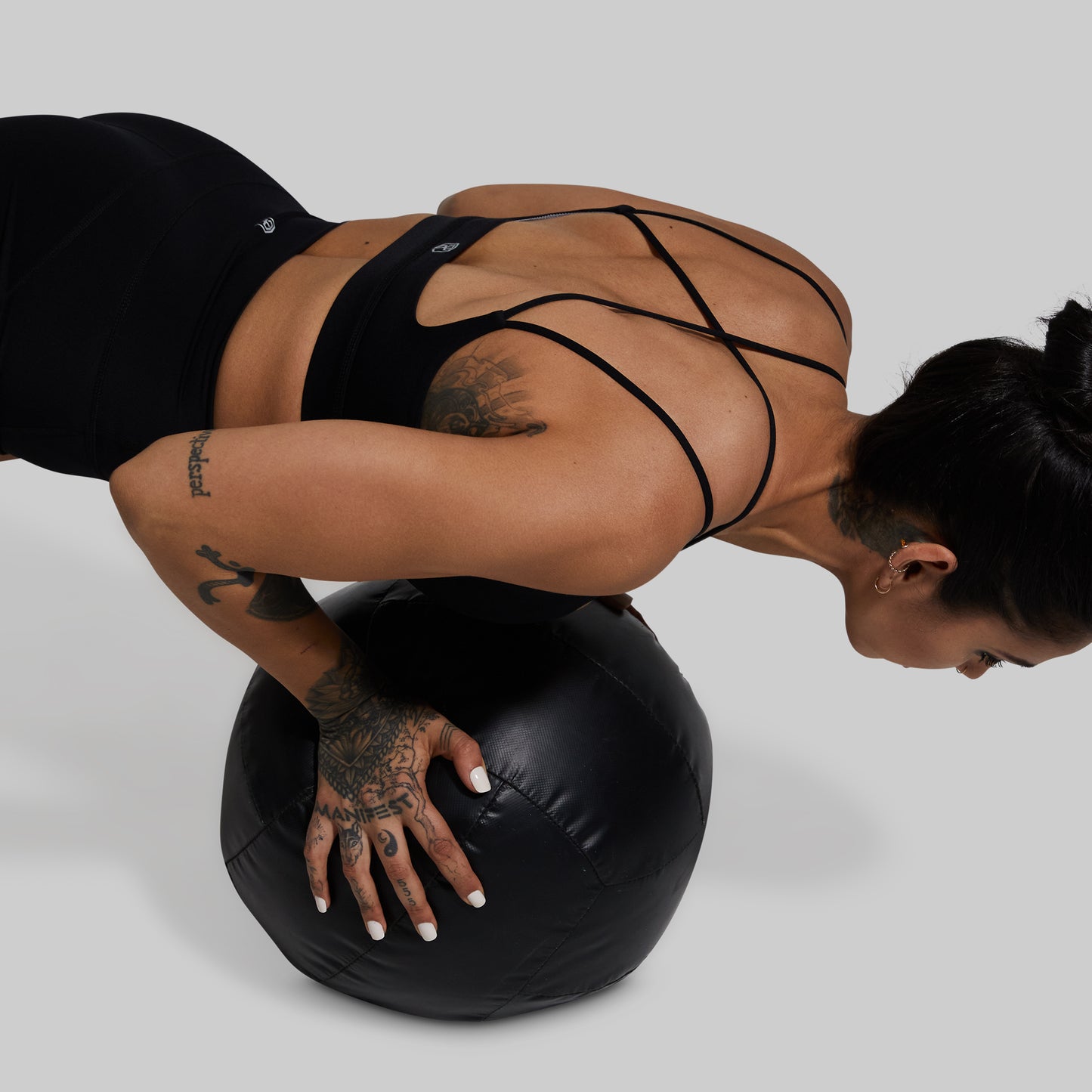 Person exercising on a black stability ball against a gray background