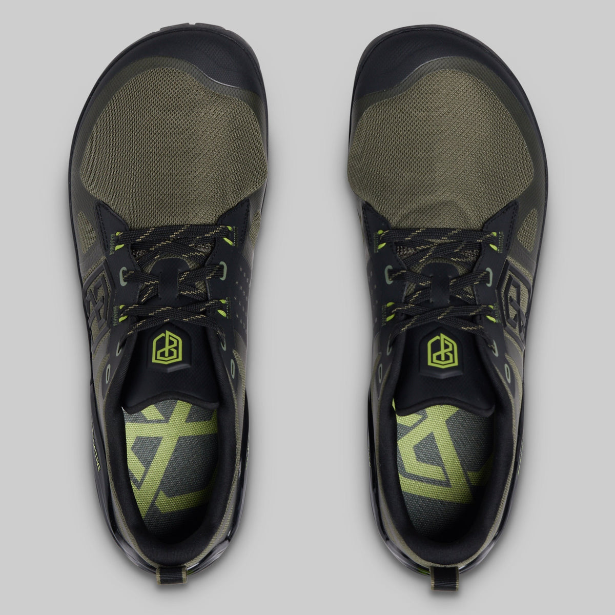 A pair of athletic minimalist training shoes shown from a top-down view on a light gray background. The shoes feature a black and olive green colorway with neon yellow-green accents on the laces, logo, and insole.