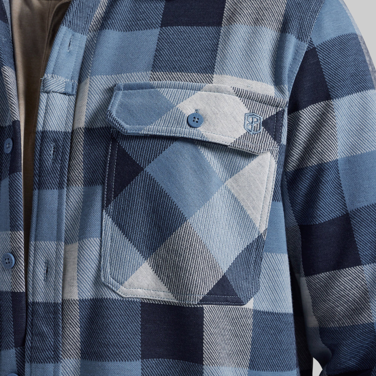 Close-up of a blue and navy plaid flannel shirt jacket with a chest pocket and button closure.