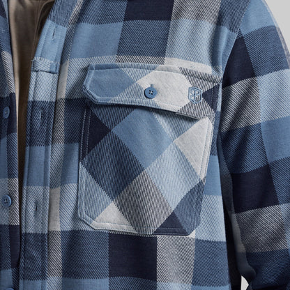 Close-up of a blue and navy plaid flannel shirt jacket with a chest pocket and button closure.