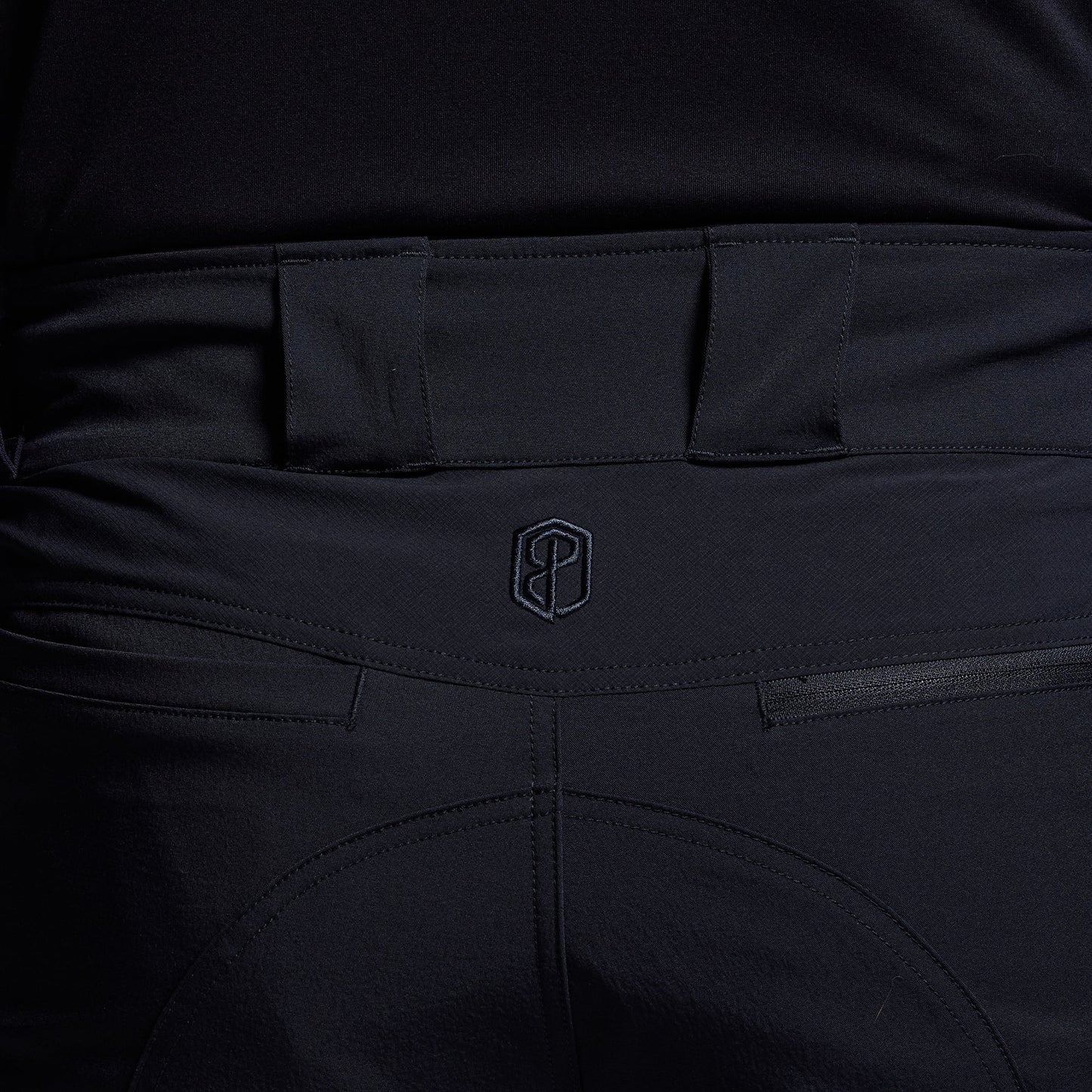 Close-up of blue pants with a brand logo on the waistband.