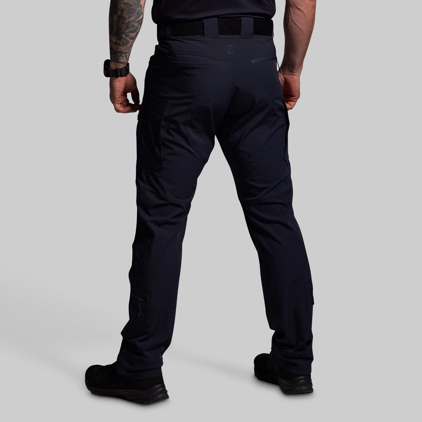 Person wearing blue tactical pants on a gray background