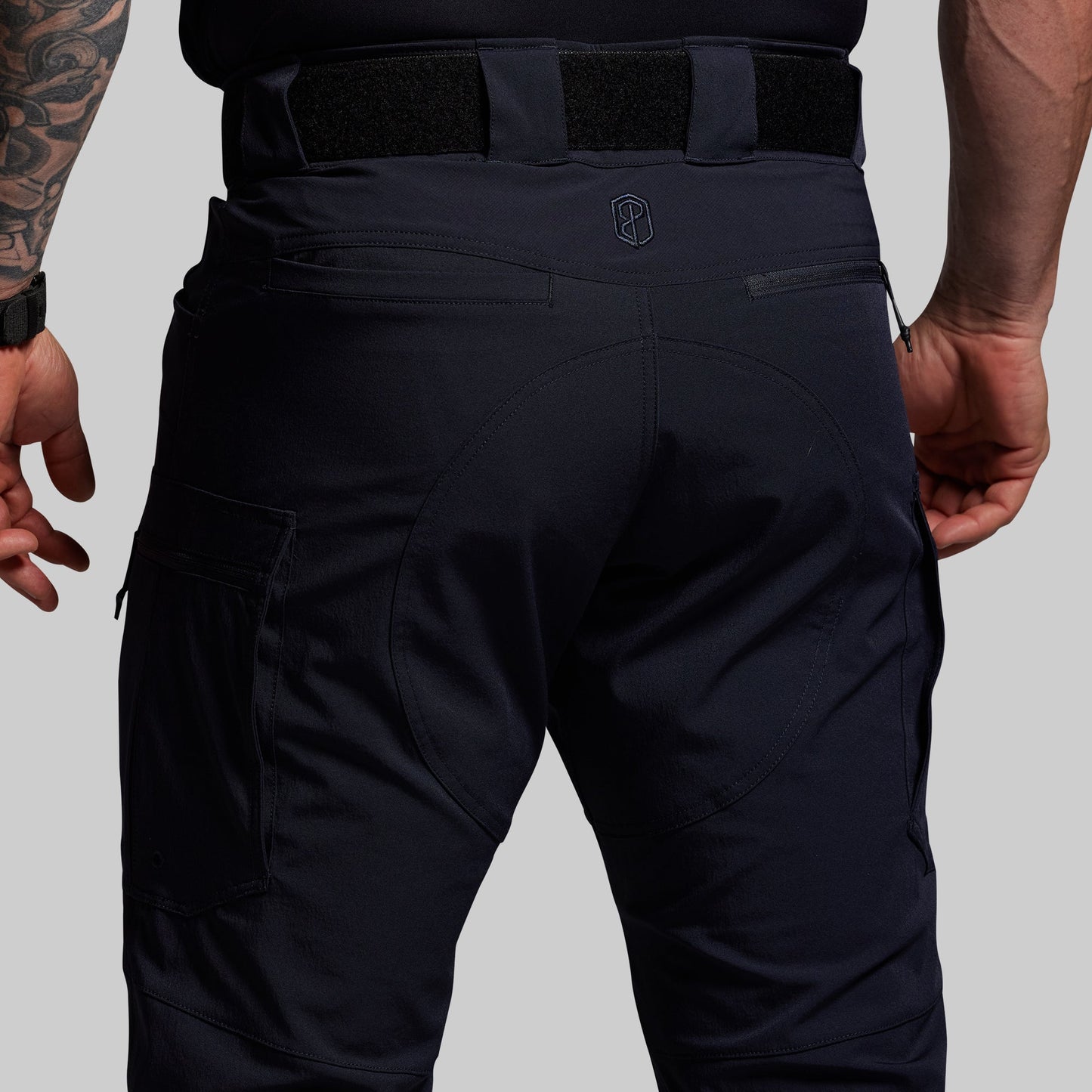 Blue tactical pants worn by a person on a gray background