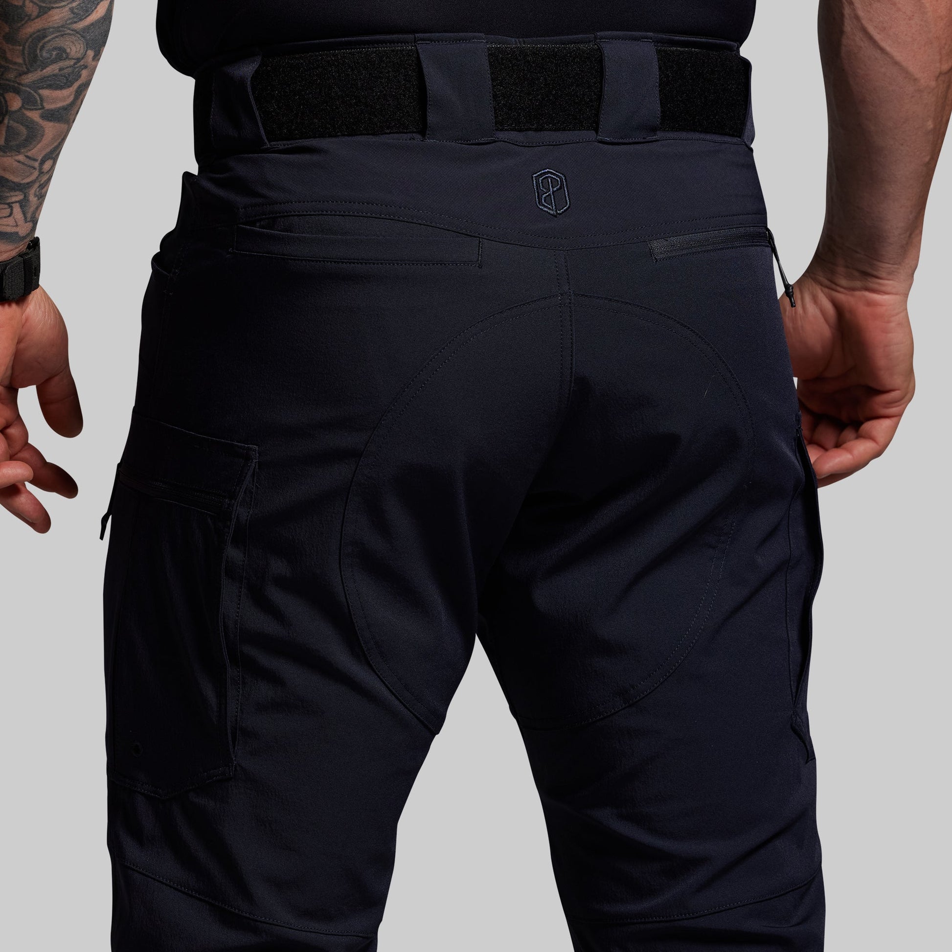 Blue tactical pants worn by a person on a gray background