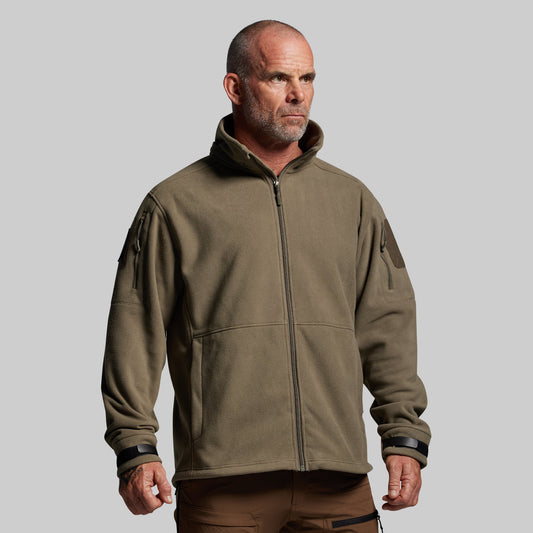 Man wearing a green tactical jacket on a gray background