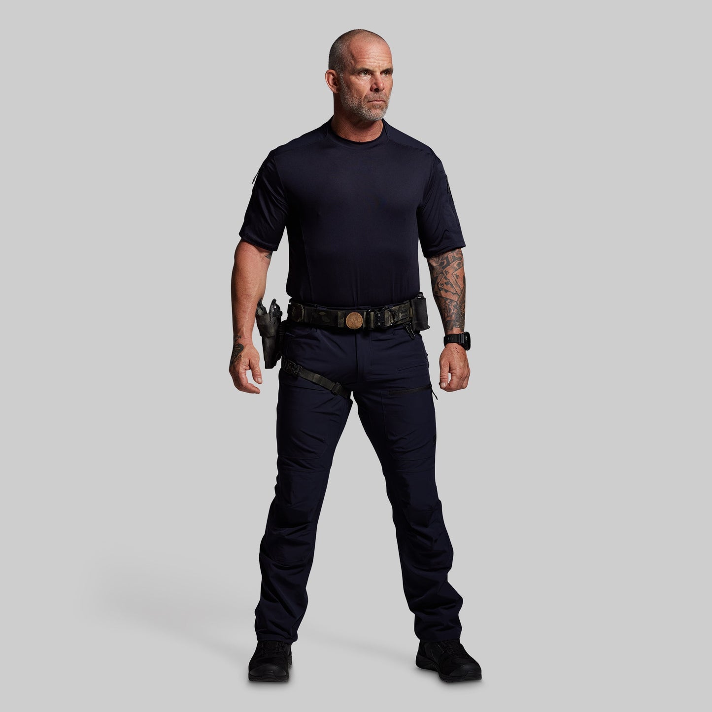 Man wearing a blue outfit with tactical gear on a gray background