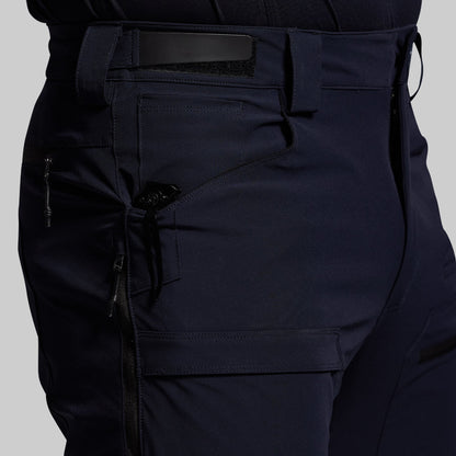 Close-up of dark blue outdoor pants with multiple pockets on a light gray background