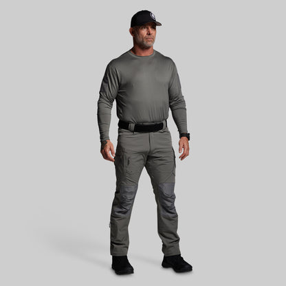 Man wearing a gray long-sleeve shirt and pants with a black cap on a light gray background