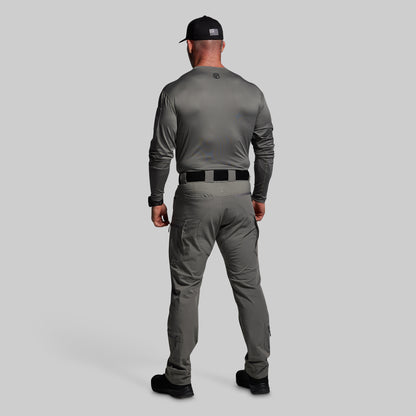 Man wearing a gray long-sleeve shirt and pants with a black cap on a light gray background