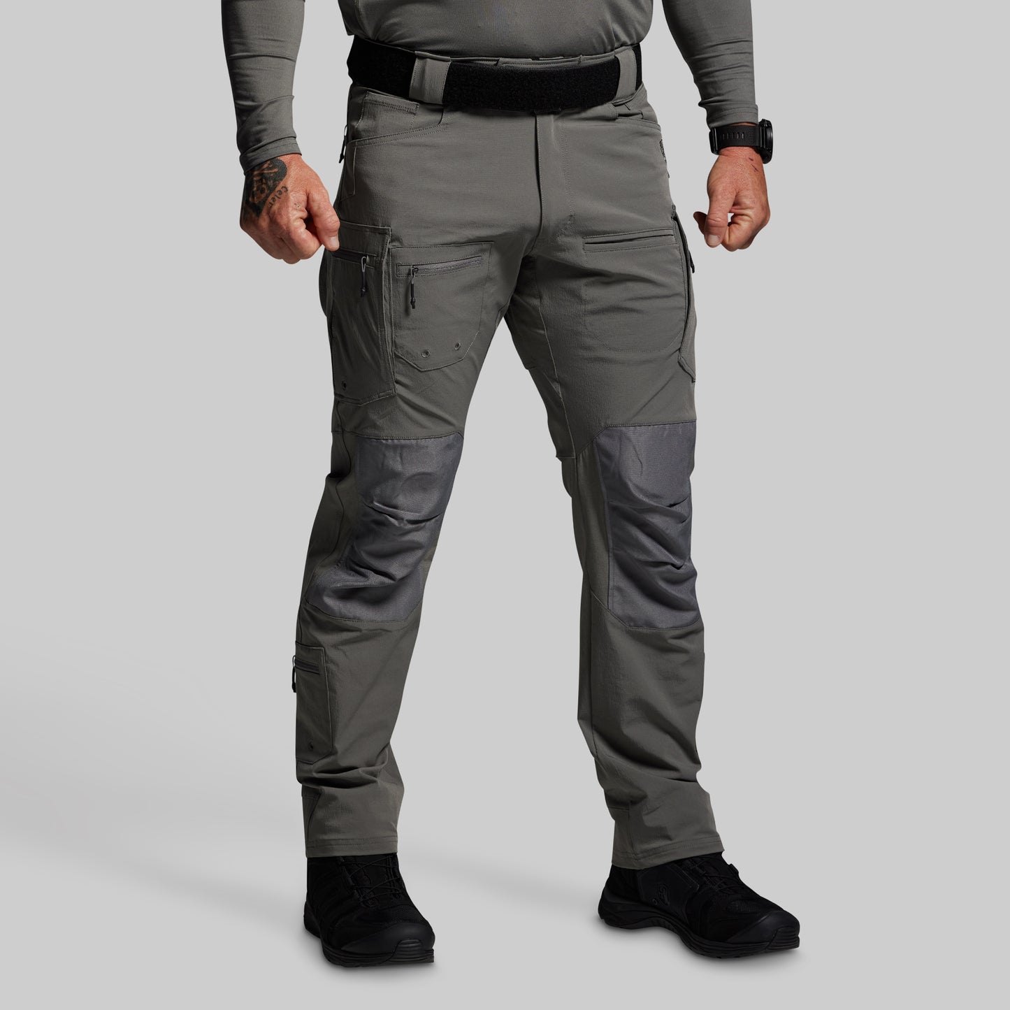 Person wearing gray tactical pants on a light gray background