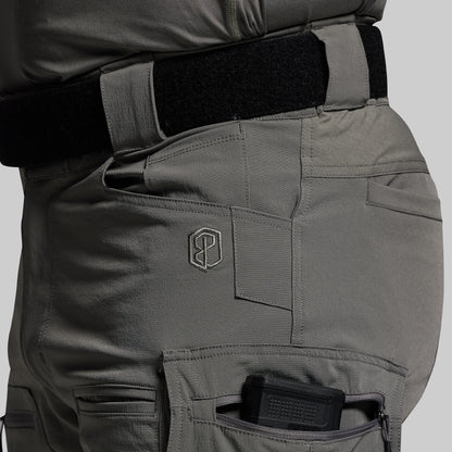 Close-up of tactical pants with a visible brand logo on a gray background
