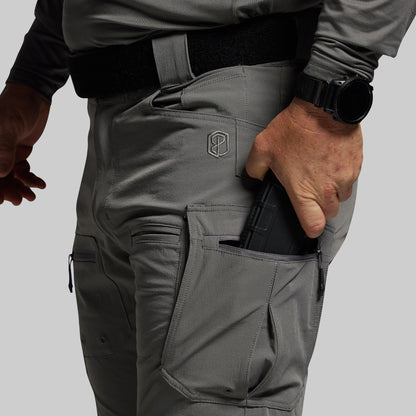 Person wearing gray tactical pants with a visible brand logo on a light gray background