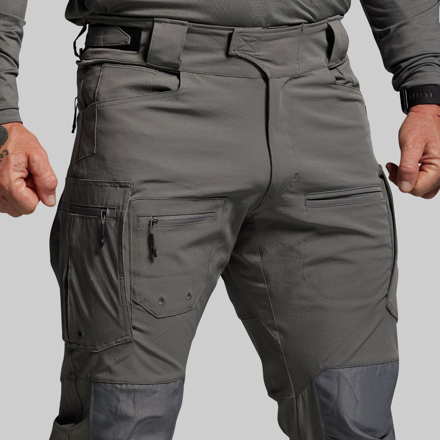 Gray tactical pants with multiple pockets on a plain background