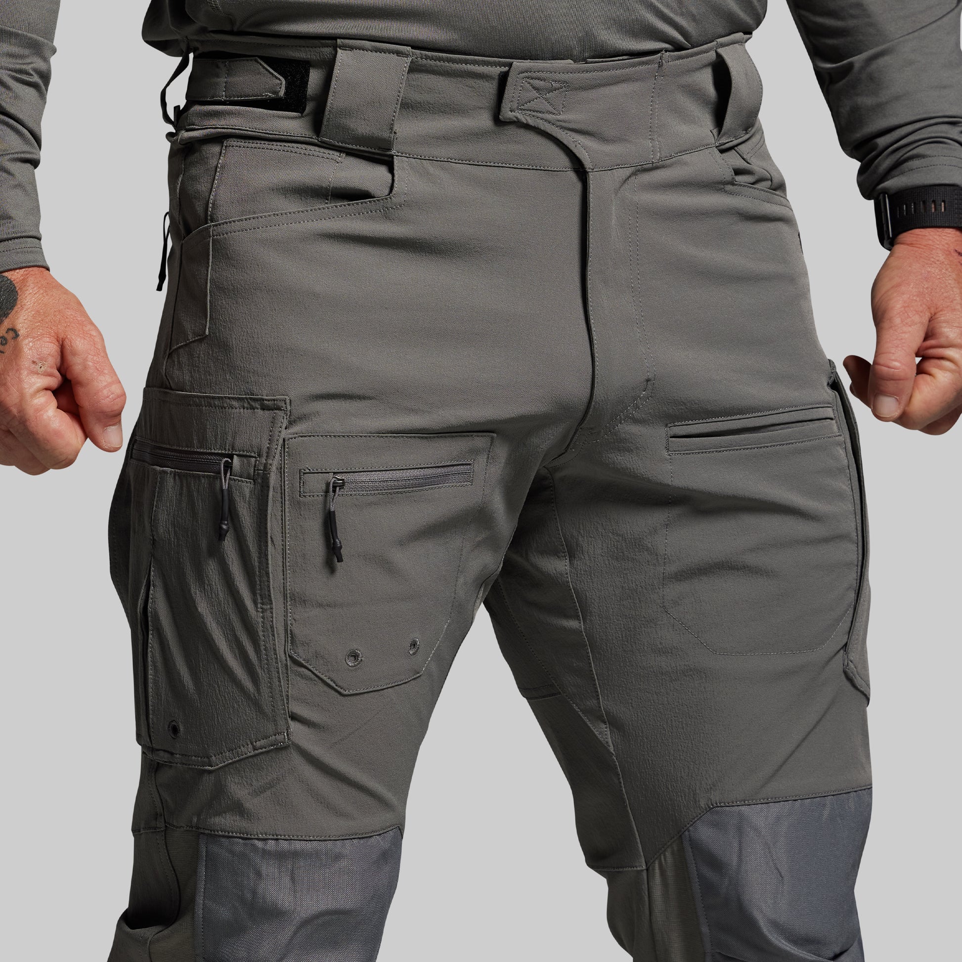 Gray tactical pants with multiple pockets on a plain background
