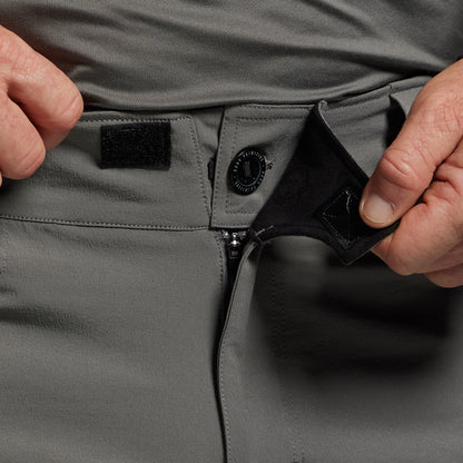 Person adjusting the waistband of gray tactical pants.