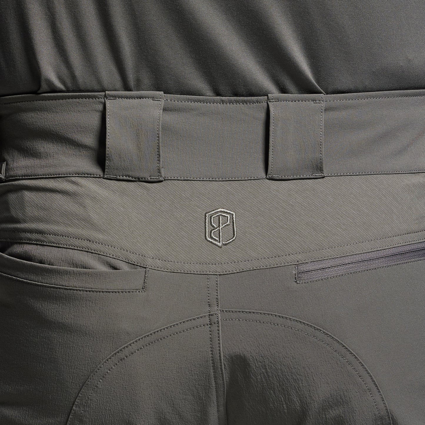 Close-up of gray tactical pants with a brand logo on the waistband.