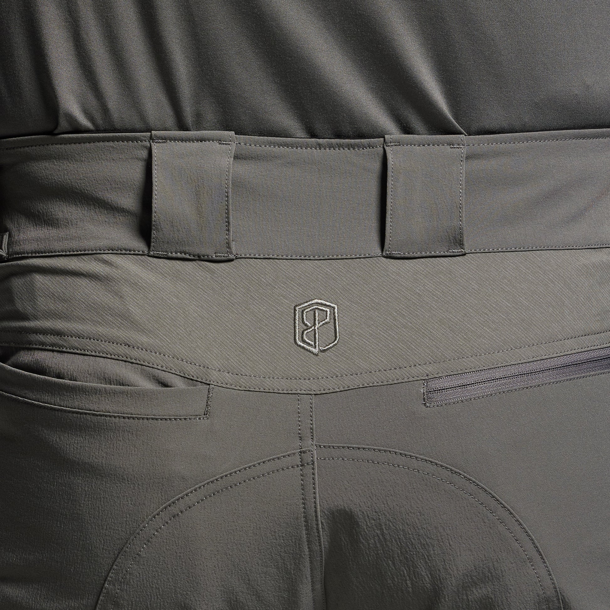 Close-up of gray tactical pants with a brand logo on the waistband.