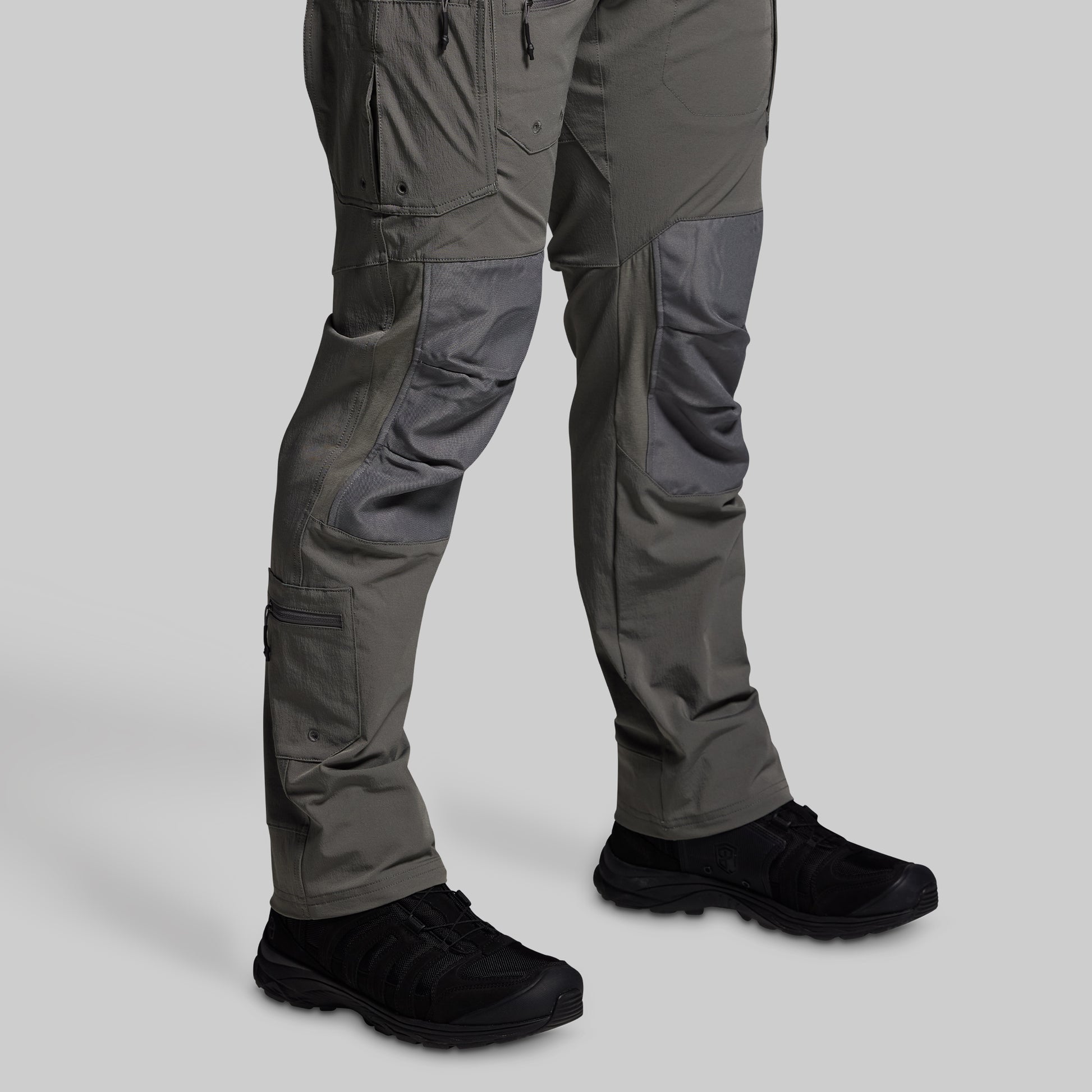 Gray tactical pants with black shoes on a light gray background