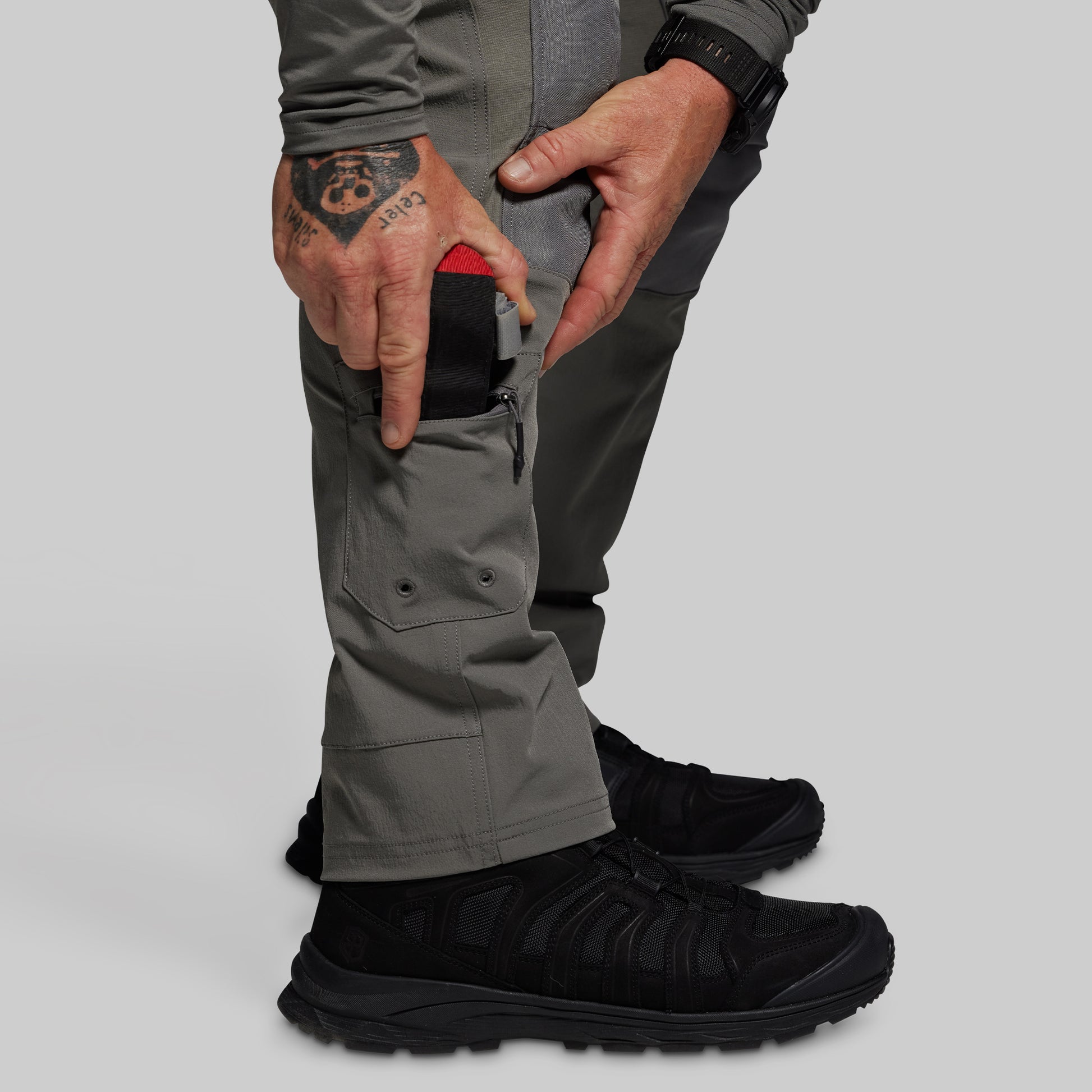 Person wearing gray pants and black boots on a light gray background