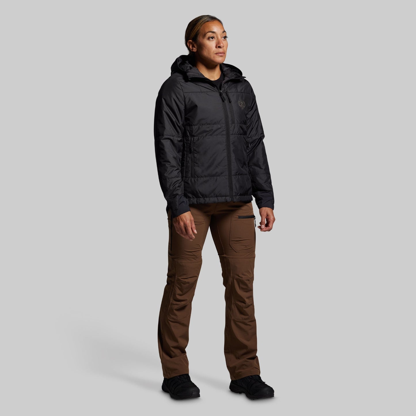 Person wearing a black jacket and brown pants on a gray background