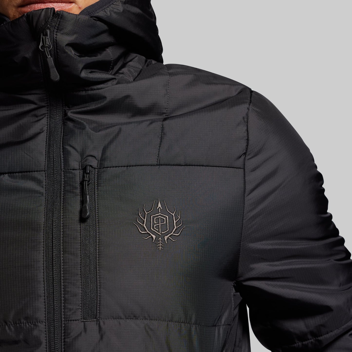 Black jacket with a logo on the chest against a gray background