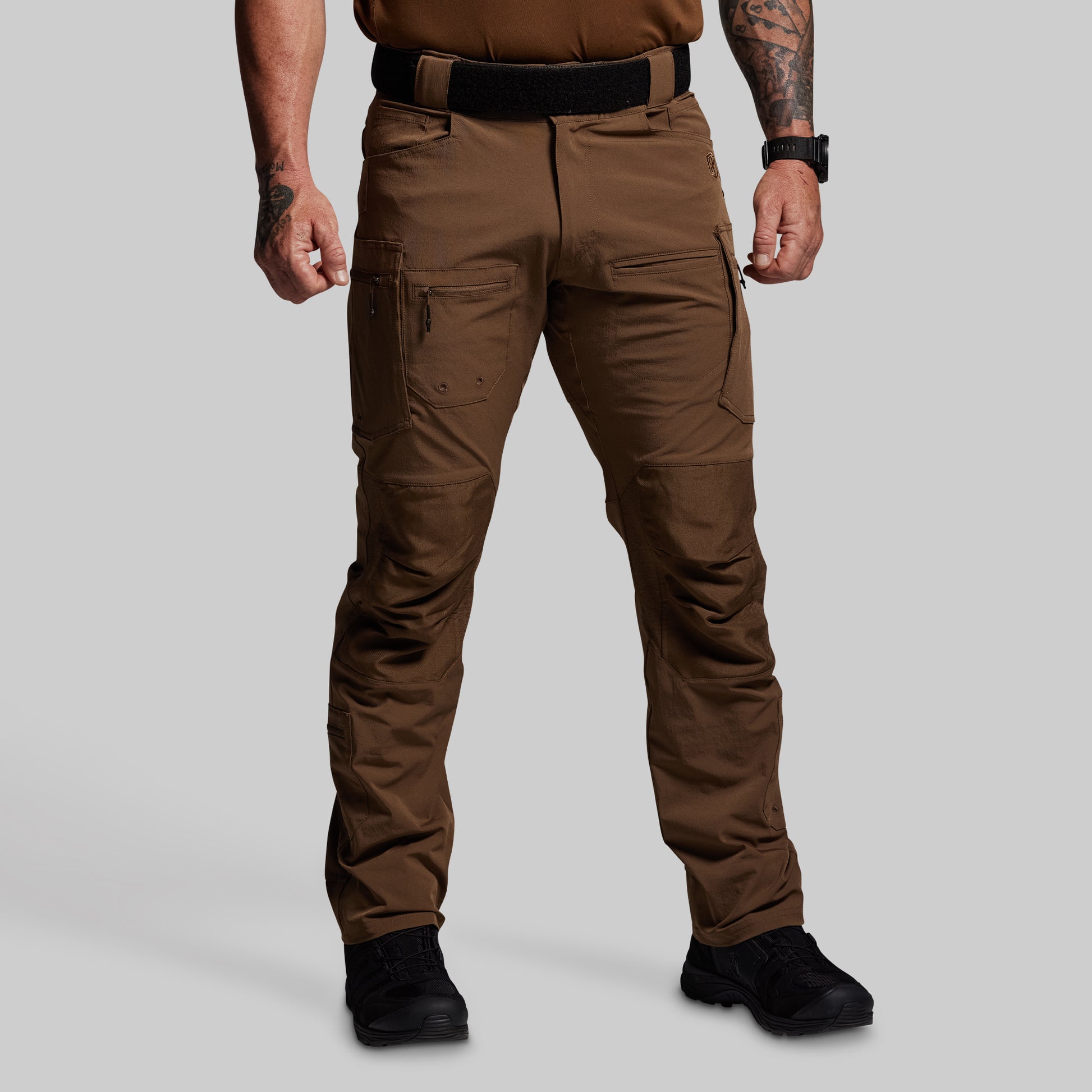 Person wearing brown tactical pants on a gray background